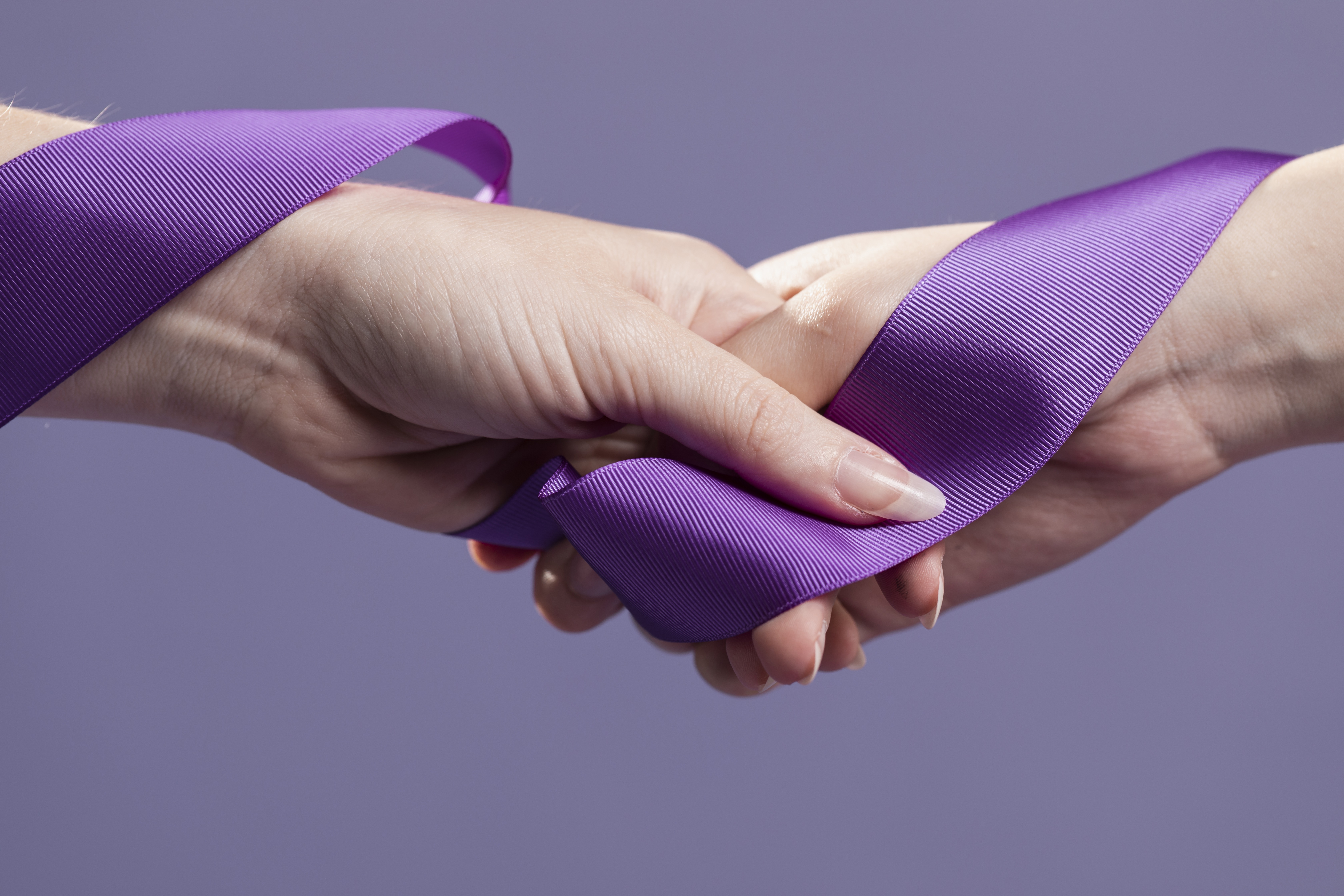 Mãos unidas com laço roxo